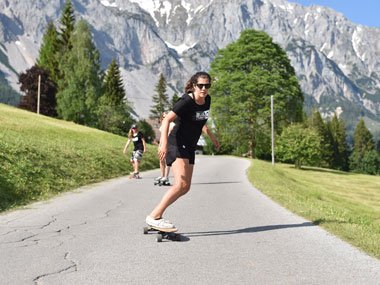 Longboard team rider on an Alpine road in Blue Tomato clothing