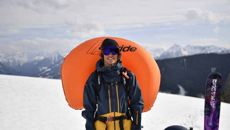 Freerider with an inflated Scott Alpride system standing outside next to his skis
