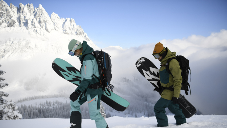 Zwei Snowboarder gehen zu fuß mit ihrem Snowboard in der Hand