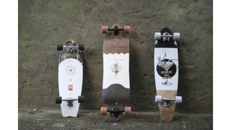 Different cruisers and longboards in front of a wall