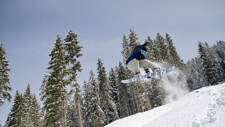 Ein Snowboarder springt abseits der Piste in unberührten Neuschnee