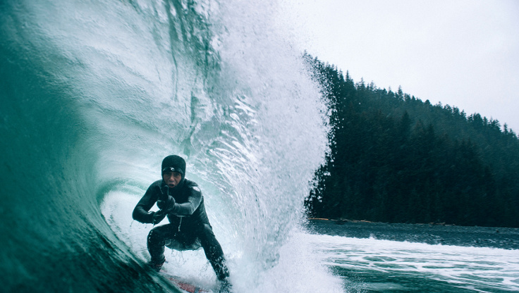 Surfer surfing in the cold waters of Alaska