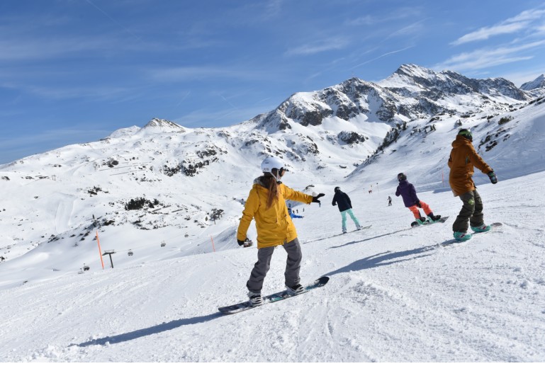 Snowboarding pupils following each other on the slope