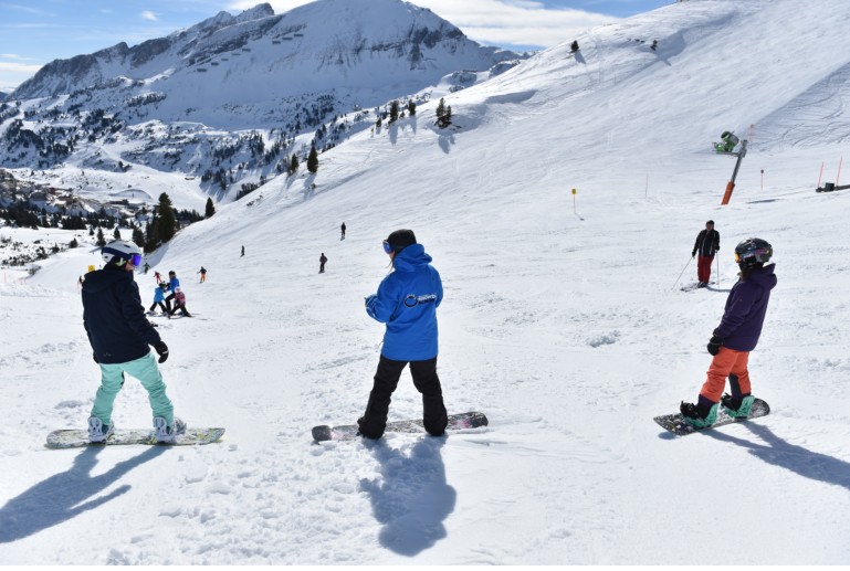 Snowboardlehrer erklärt den Schülern die nächste Übung