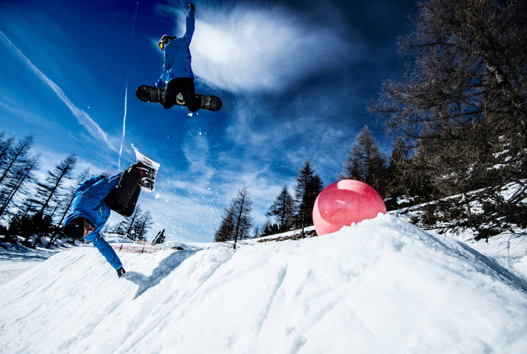 Two Blue Tomato Snowboard instructors jumping over a corner