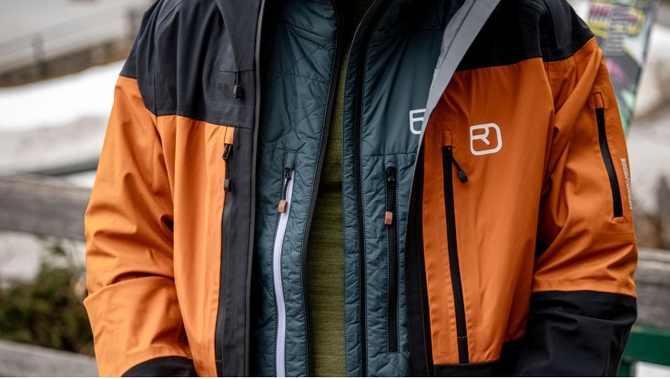 Snowboarder shows different layers of his functional clothing