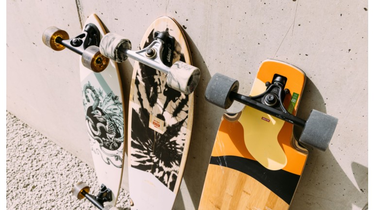 Different cruisers and longboards in front of a wall