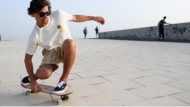 Skateboarder fährt im Morgengrauen mit seinem Cruiser auf einer Straße in Spanien