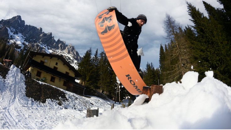 Freestyle snowboarder doing a trick on a box in the snowpark, with a soft board