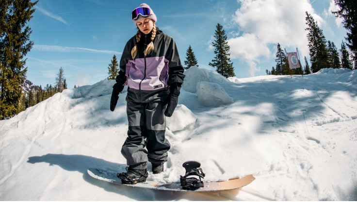 Lachende Snowboarderin liegt im Schnee