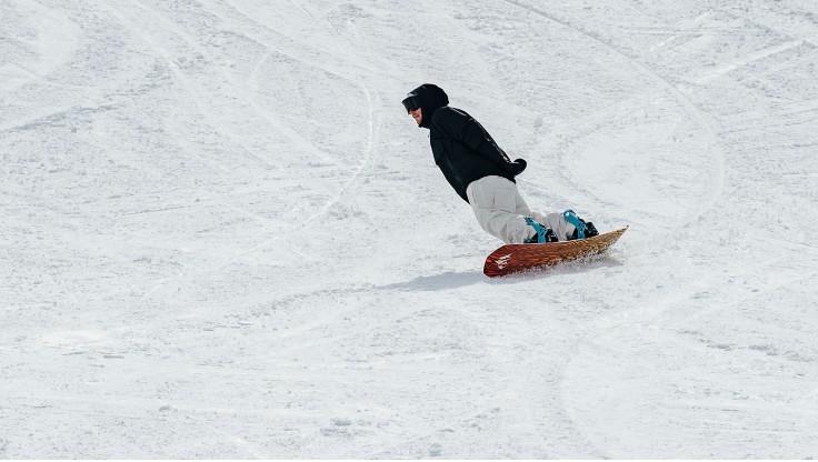 Zwei Freunde carven mit Snowboards auf der Piste