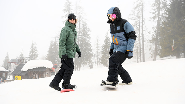 a man and a woman learning to snowboard