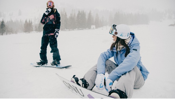 un hombre y una mujer aprendiendo a hacer snowboard