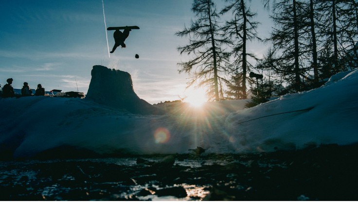 Un snowboarder saute par-dessus un gros rocher