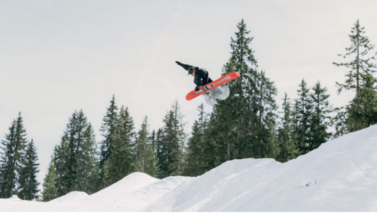 Snowboarder jumps over a large rock