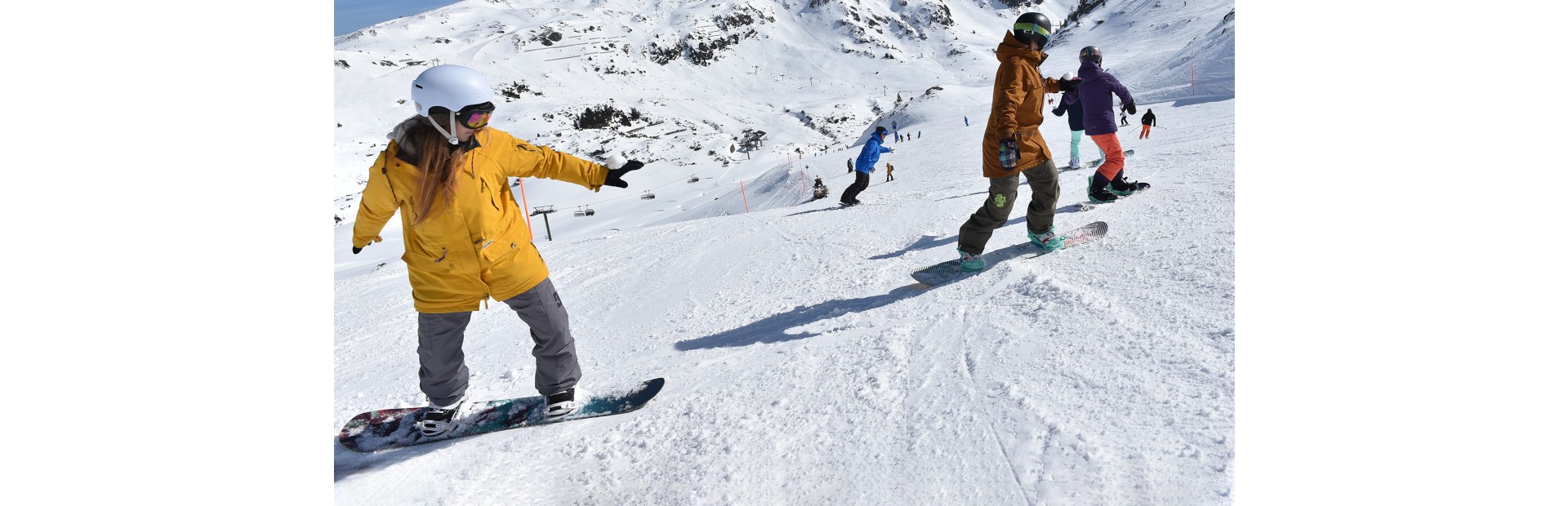 Snowboardschüler fahren hintereinander auf der Piste