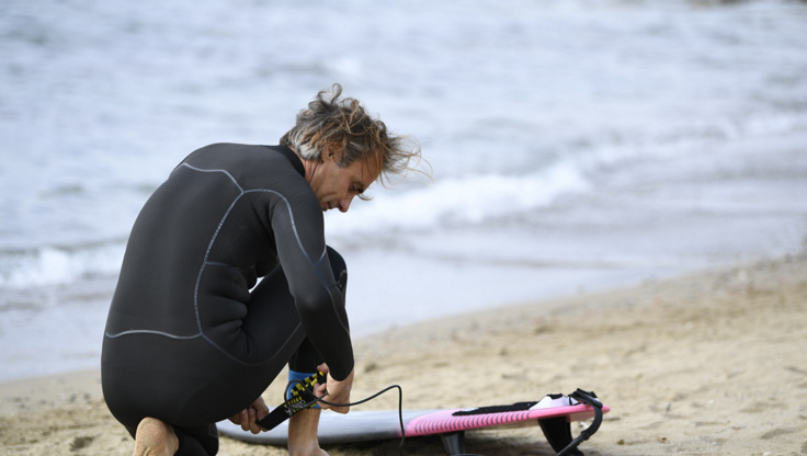 Mädchen im Meer neben ihrem Surfboard mit der Leash an ihrem Knöchel befestigt