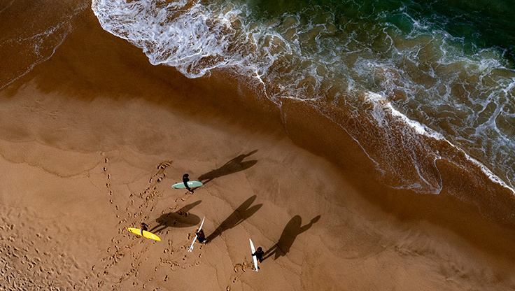 To nybegynnere på stranden, som bærer surfebrettene sine