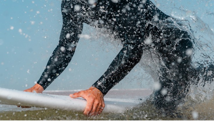 Surfer felice dopo una sessione in acqua con la sua muta senza cerniera
