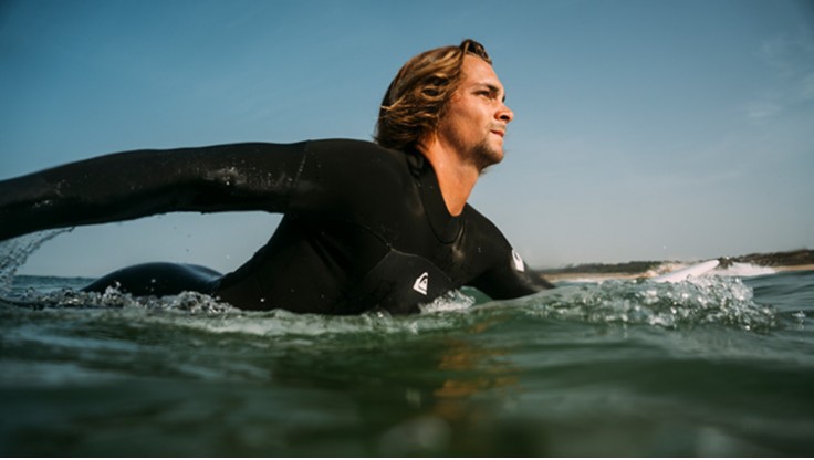 Surfer paddeling in cold water in a full wetsuit