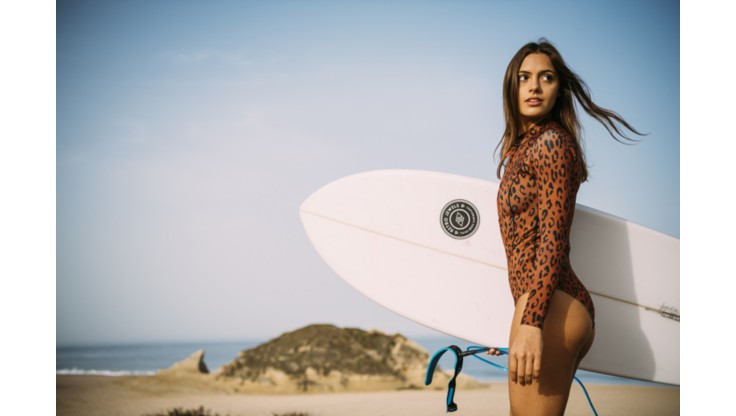 Girl surfer going in the water in a 1 mm springsuit