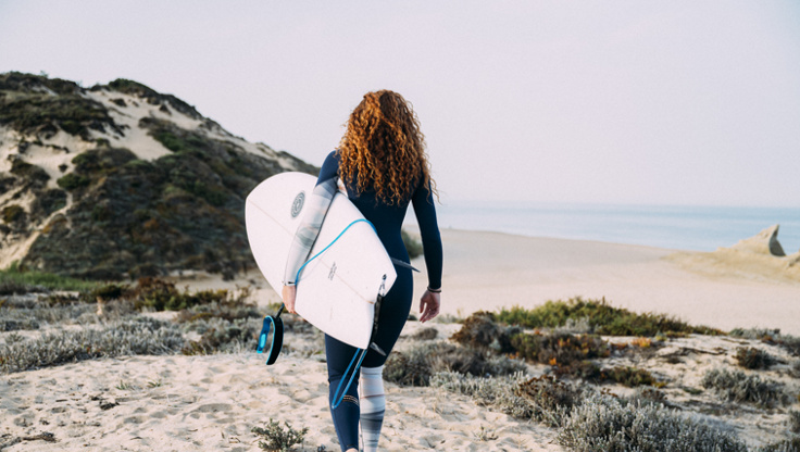 Surfer Girl macht sich bereit mit einem 3/2 Neoprenanzug